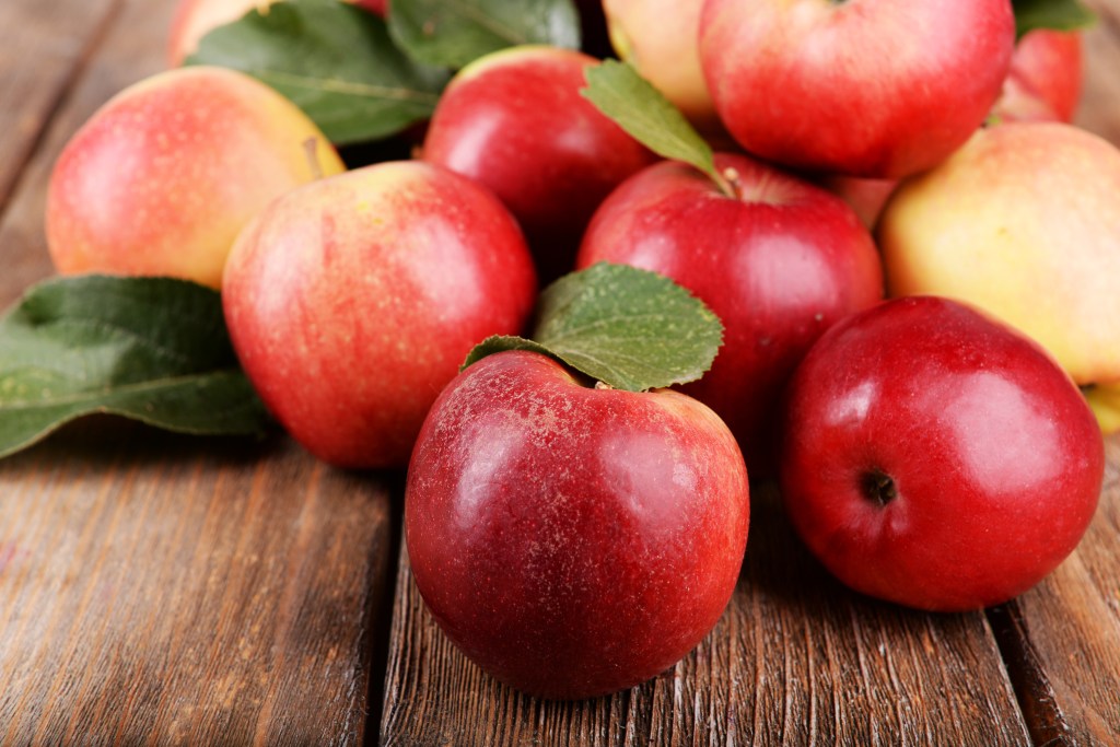 Bunch of ripe red apples on a wooden surface